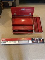 Photo showing the open red metal Craftsman toolbox with two drawers and removable tray alongside the boxed Cargo Bar storage net.