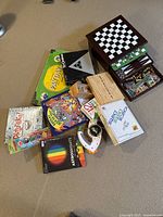 Overview of all items in the game bundle showing game boxes, Bop It Extreme, Astrobrights paper, paint pots, multi-game box, and books.