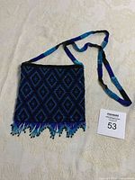 Front view of beaded purse showing diamond pattern and beaded fringe, with strap partially coiled