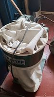 View of white cloth dust collection bag with Craftex label and some attached hoses