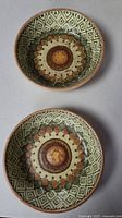 Two small dishes with geometric and floral hand-decorated pattern, green brown and tan colors