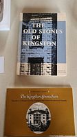 Two Kingston history books by Margret Angus stacked on a light surface, showing full covers