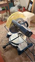 Full view of blue Ryobi chop miter saw with yellow blade guard on 10-inch blade and adjustable base for angle cuts