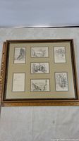 Full view of the framed set showing seven individual sketch prints arranged in two rows with a cream mat and gold trimmed wooden frame.