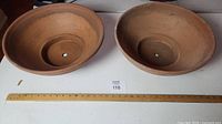 Top view of two large terracotta planters side by side showing interior and central drainage hole