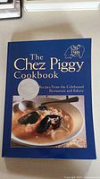 Front cover of 'The Chez Piggy Cookbook' softcover book showing title, a seafood dish image, and a silver award sticker.