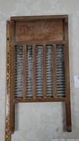 Full view of the vintage wooden washing scrub board showing the metal scrubbing surface and wooden frame.