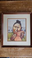 Full view of framed art print titled "A Greenlandic Woman's Chores" by William Kurelek, measuring 17 x 15 inches with a wooden frame.