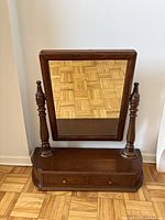 Front angled view of antique mahogany dresser mirror with visible reflection and two drawers at base