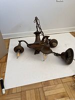 Top view of hanging light fixture showing three flagged arms with bulbs and bell-shaped decorative elements