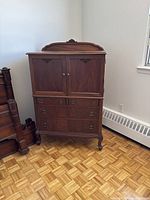 Front elevation of closed piece showing cabinet doors, drawers, carved crest and bracket feet