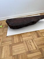 Photo showing side length and irregular natural edges of the walnut wood shelf on parquet floor.