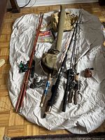Full lot spread showing six fishing rods, reels, and two carrying bags on a white cloth.
