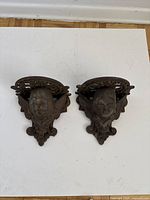 Front view of the two iron sconces showing angel faces and decorative tops