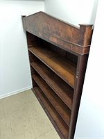 Side angle showing the four shelves of the mahogany bookshelf against a wall, showcasing the wood grain and finish.