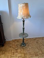 Full view of the floor lamp showing the shade, green marble column, and brass base against a white wall.