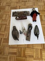 Overview of all items on white paper showing doll, five bird figurines, and two decorative carved pieces.