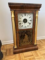 Front view of the Seth Thomas walnut mantle clock showing gold columns and clock face.