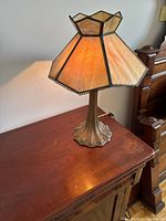Side view showing the full lamp and brass base with floral details on a wooden surface.