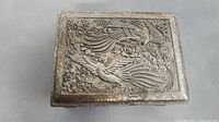 Top view showing rectangular pewter box with embossed design of two birds and floral decorations on lid.