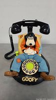 Front view of the Brooktel Goofy telephone character phone displaying Goofy sitting in chair with rotary dial and handset.