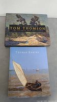 Front covers of Tom Thomson and Thomas Eakins books, showing artwork and titles.