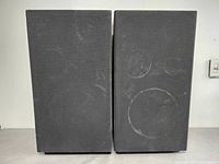 Front view of pair of AUDIO TECH Pro Series PS-25 speakers with black grille covers, showing minor wear marks on fabric.