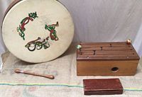 Bodhran drum face with colorful Celtic-inspired artwork, wooden tongue drum, and wooden block with mallet