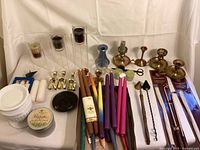 Full view of all candles, brass candle holders, snuffers, and accessories arranged on a white surface