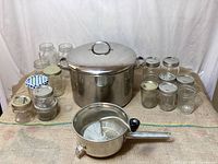 Overview of all items on fabric surface including canning jars, stock pot, and Foley food mill.