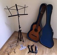 Full lot arranged: guitar in case, music stand, sheet music holders, wall hangers, cable