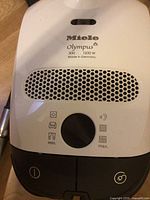 Close-up top view of white Miele Olympus vacuum cleaner control panel showing power dial and vents.