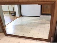 Large wall mirror in wood frame with visible floor reflection