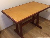 Full view of rectangular two-tone wooden table showing lighter colored top and dark base.