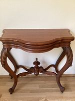 Front view of vintage wooden side table showing carved legs and shaped top surface