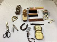 Overview of the assortment laid out on bedding showing scissors, razors, brushes, combs, a horseshoe and additional small tools and accessories.