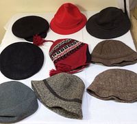Overview of all nine women's wool hats in various styles and colors displayed on white cloth.