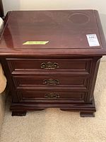 Front view of nightstand showing three drawers and bracket feet