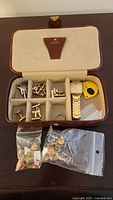Overhead view of open Hamilton case with watch, tools, cufflinks, pins