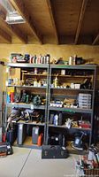 Front view of two metal shelving units with assorted stored items including tools, containers, and boxes