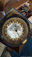 Full top-down view of the marine compass inside a box, showing the compass face and cracked glass.