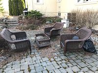 Four-piece patio furniture set on paved outdoor surface: two chairs, one loveseat and one square side table frame