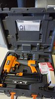 Ridgid pneumatic nailer in black and orange with case, accessories, and manual