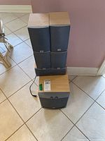 Photo showing all six speakers together with four bookshelf speakers, one center channel speaker, and one subwoofer stacked on the floor.