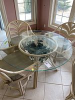 Full view of the square glass top with cream rattan chairs around it, showing the table's design and top surface.