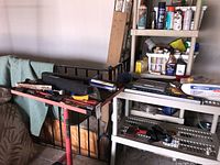 Overview of tools spread on red adjustable height tool cart and white shelving unit, showing various items including cases, spray cans, and hand tools