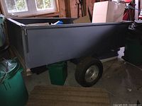Front-side view of gray metal utility trailer with items inside