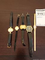 Five watches side by side on table showing entire lot