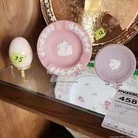 View of the lot showing two lavender Wedgwood jasperware dishes and a pale stone egg in a brass holder