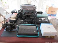 View of all items spread on table including Contax 139 camera, HP Mini laptop, camera case, flash, cords, and other accessories.